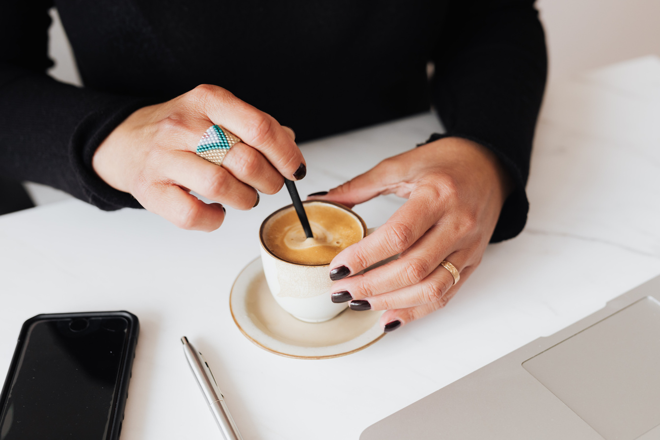 Crop woman with stylish ring stirring hot espresso